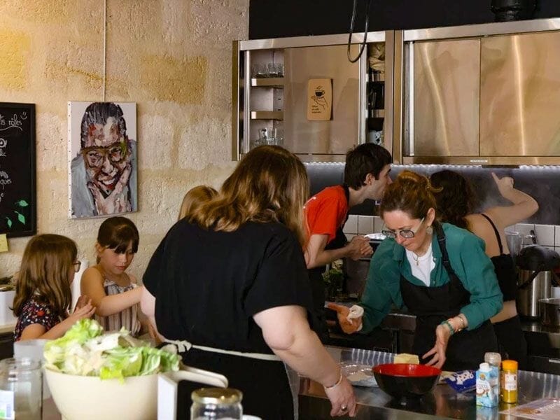 Des participants concentrés dans un cours de cuisine à Bordeaux, préparant des plats dans une ambiance conviviale et chaleureuse.