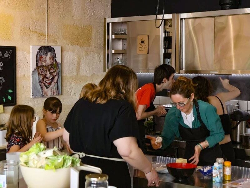 Des participants concentrés dans un cours de cuisine à Bordeaux, préparant des plats dans une ambiance conviviale et chaleureuse.