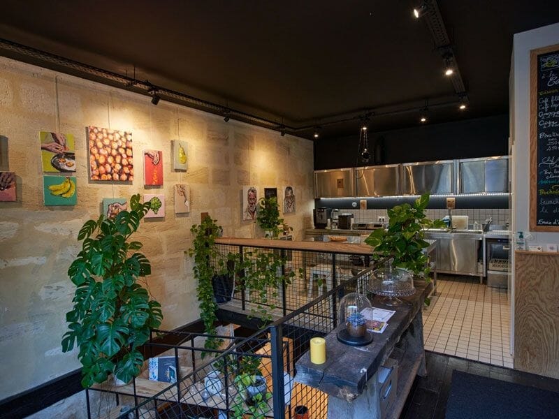 Intérieur d'une cuisine professionnelle avec plantes vertes, murs en pierre et équipements modernes bien rangés.