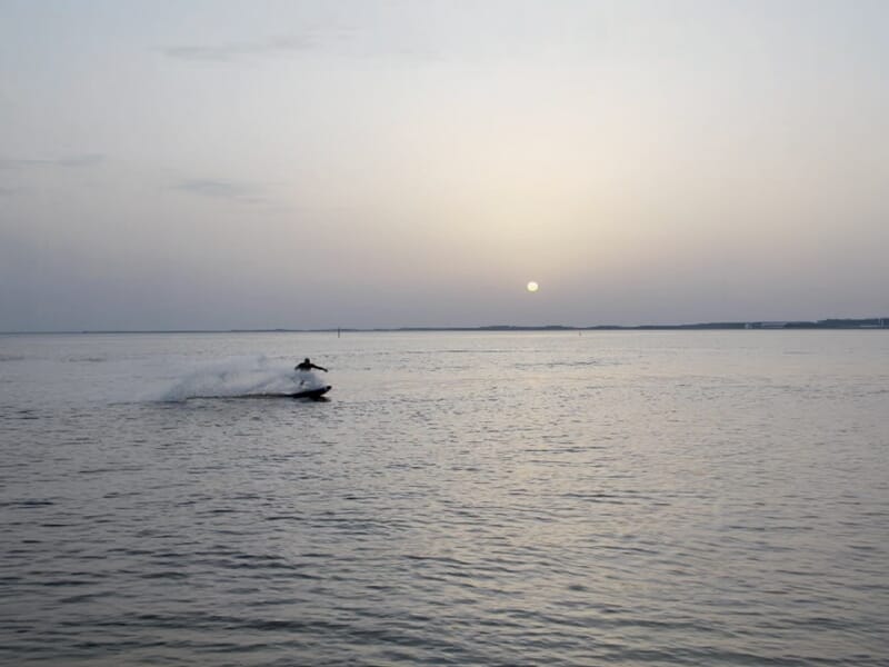 Personne sur un surf électrique glissant sur l'eau calme au coucher du soleil à Andernos-les-Bains.