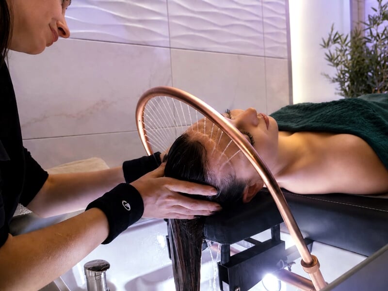 Personne recevant un soin capillaire avec un professionnel dans un environnement relaxant et moderne.