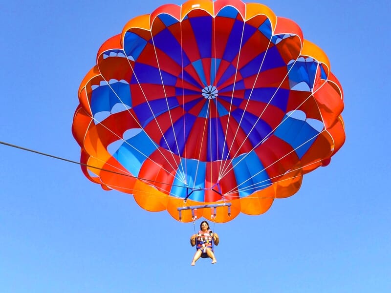 Personne seule en parachute ascensionnel sous un parachute coloré orange, bleu et rouge, volant dans le ciel.
