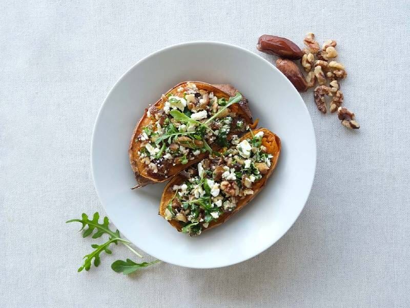 Assiette avec deux tranches de patate douce garnies de fromage, noix et roquette sur une table, réalisée lors d'un cours de cuisine près de Vannes.
