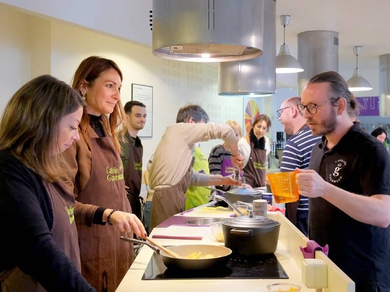 Groupe de personnes participant à un cours de cuisine dans une cuisine équipée et moderne.