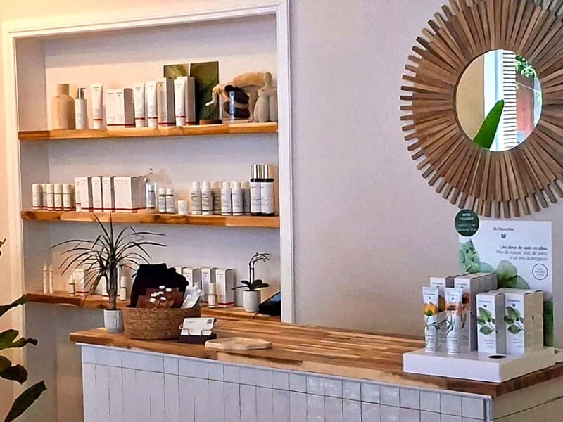 Comptoir en bois avec produits de beauté et miroir rond décoratif dans un espace de soin esthétique.