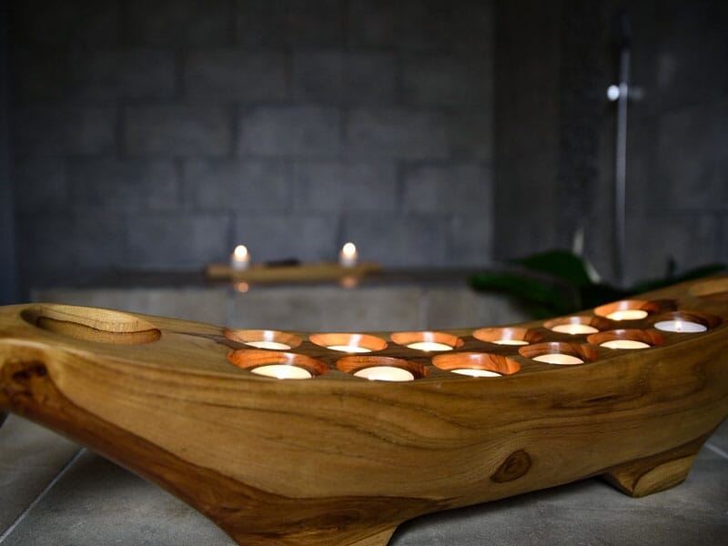 Bougeoir en bois sculpté avec plusieurs petites bougies allumées, décor zen et apaisant.