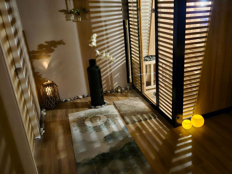 Coin détente avec tapis, vase noir, lumière tamisée et décoration zen dans un spa.