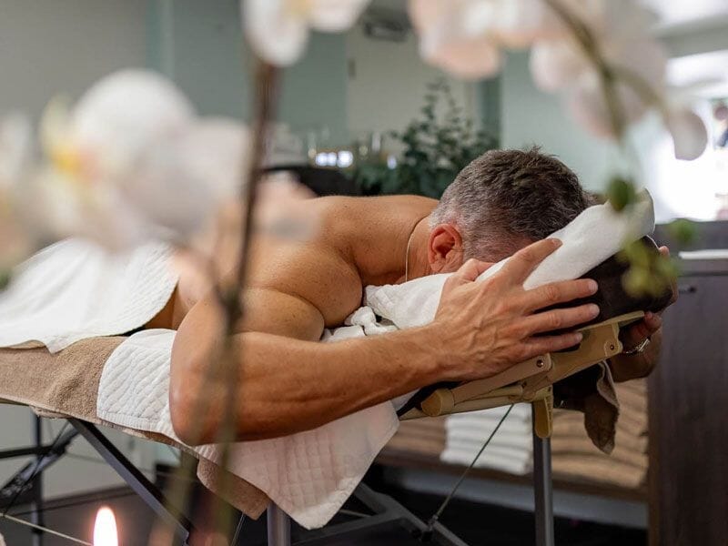 Un homme allongé sur une table de massage, recevant un soin dans un environnement calme et apaisant.