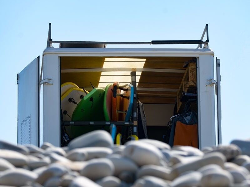 Vue arrière d'un camion ouvert avec des planches de surf colorées rangées à l'intérieur, ciel bleu en arrière-plan.