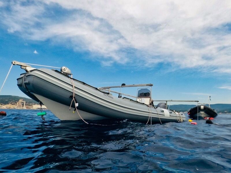 Bateau pneumatique gris flottant sur une mer calme sous un ciel partiellement nuageux à La Ciotat.