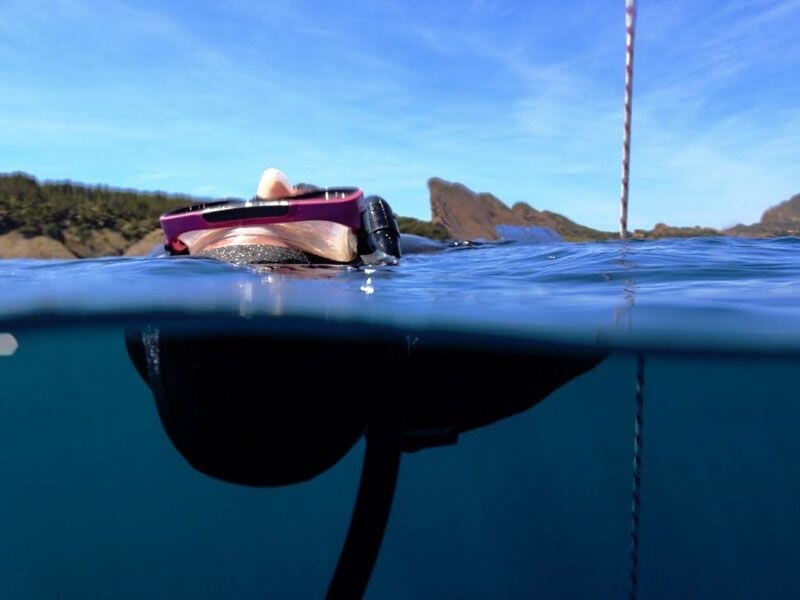 Plongeur en surface avec masque et tuba, moitié sous l'eau, moitié au-dessus, dans une mer calme.