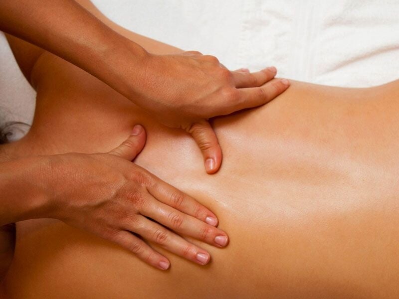 Massage du dos effectué par un professionnel dans un cadre relaxant et chaleureux.