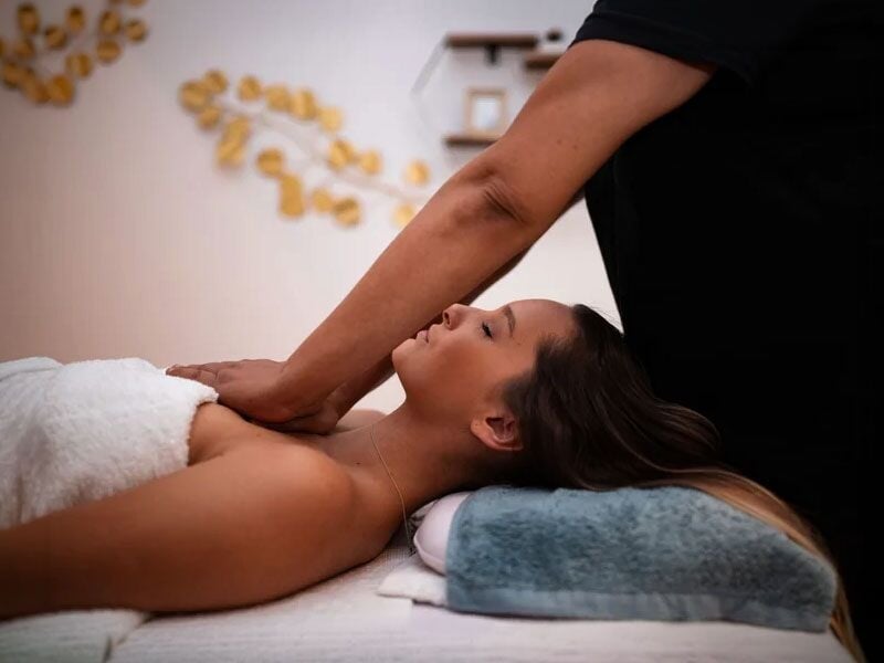 Femme allongée recevant un massage relaxant des épaules dans un spa calme et apaisant à Paris.