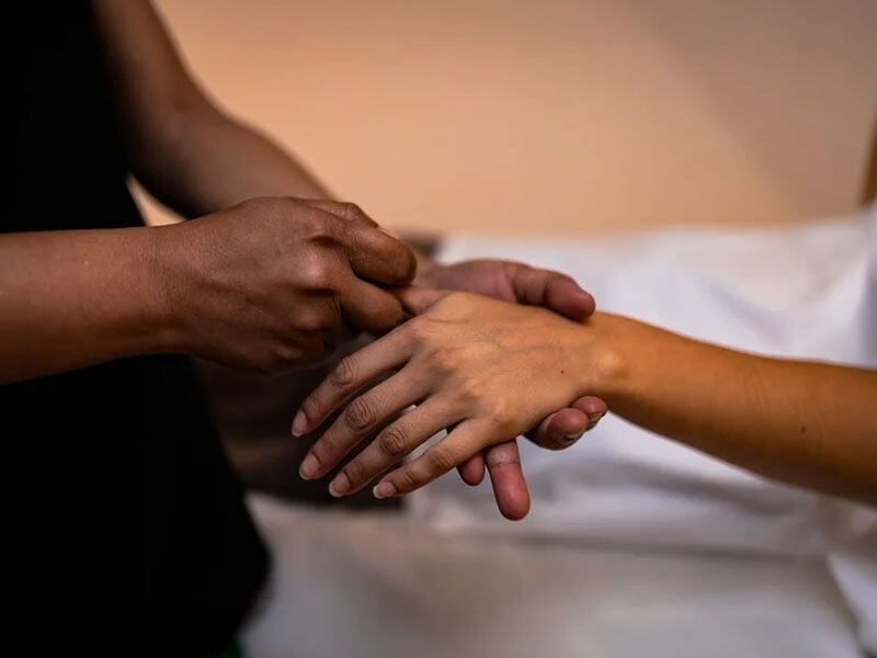 Praticien effectuant un massage des mains pour détendre et soulager le stress d'une cliente.