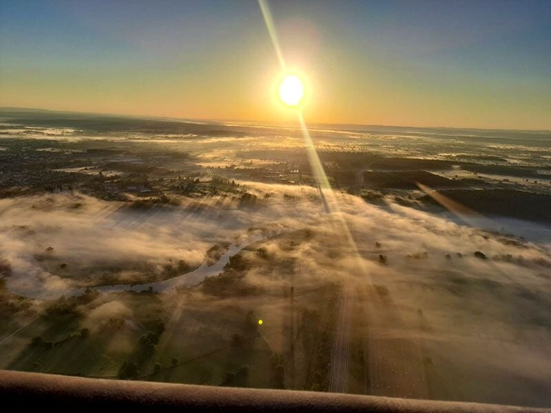 Vue aérienne au lever du soleil avec un paysage de campagne et des nappes de brouillard sur les champs et rivières.