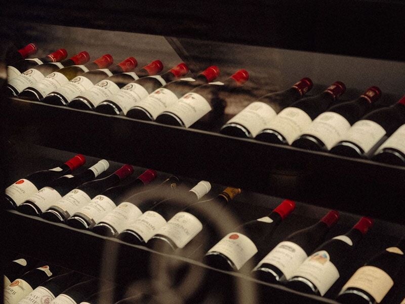 Rayons de bouteilles de vin rouge alignées dans une cave sombre, prêtes à être dégustées par les amateurs d'œnologie.