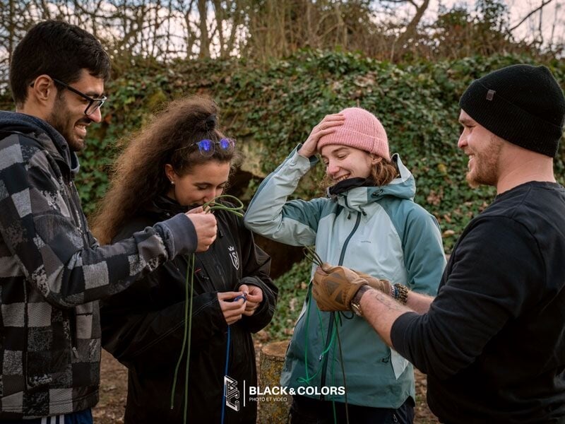 Groupe de quatre personnes souriantes en plein air, manipulant des cordes et discutant ensemble.