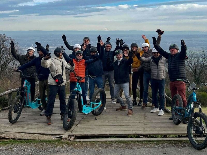 Groupe de personnes en vêtements d'hiver avec trottinettes électriques célébrant sur une plateforme en hauteur.