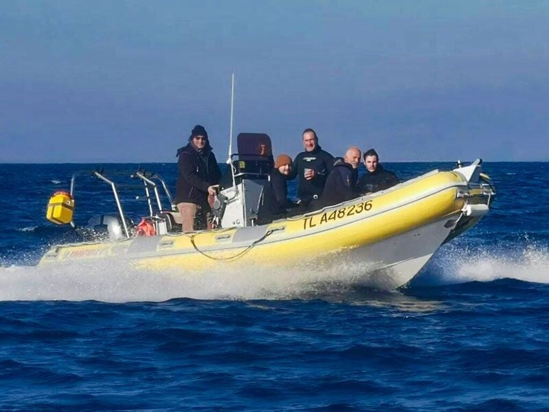 Bateau pneumatique rapide avec plusieurs personnes à bord naviguant sur une mer agitée.