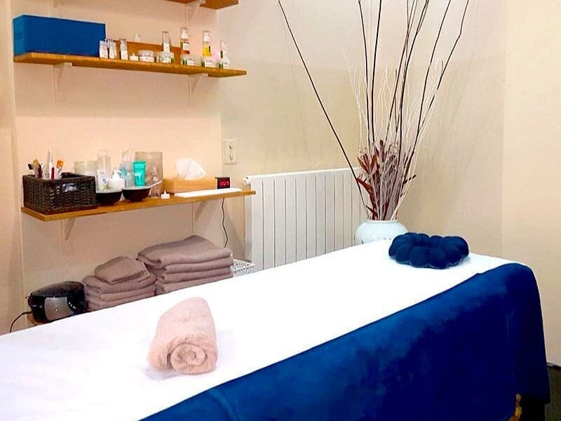 Table de massage avec serviettes roulées, ambiance chaleureuse et décor minimaliste dans une salle de spa.