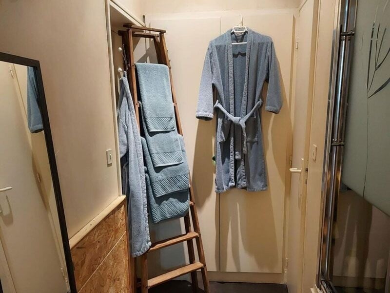 Peignoir et serviettes bleues suspendus sur une échelle en bois dans un espace spa intime et fonctionnel.