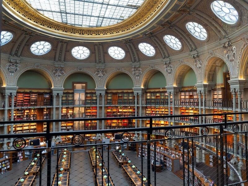 Vue panoramique d'une grande bibliothèque circulaire avec de nombreuses étagères et un plafond vitré.