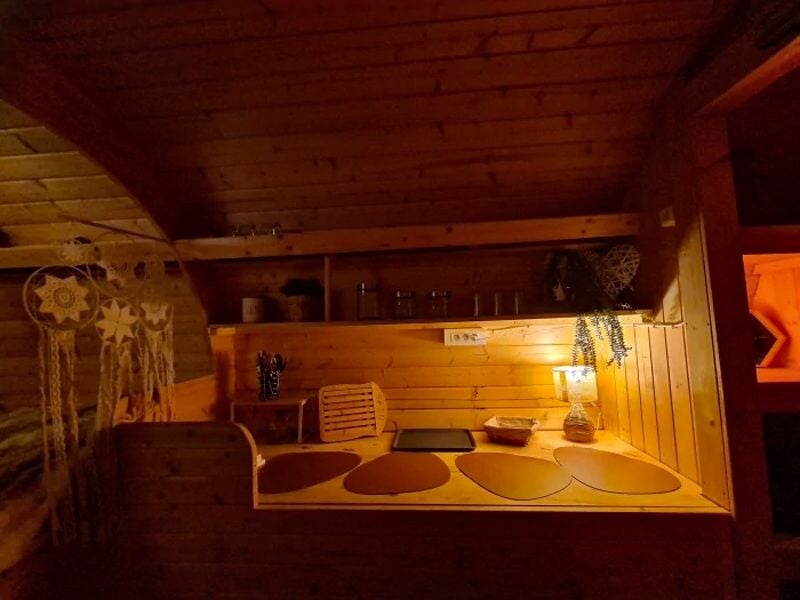 Coin bureau en bois chaleureux avec lampe, plantes et décorations suspendues dans un espace intime et cosy.
