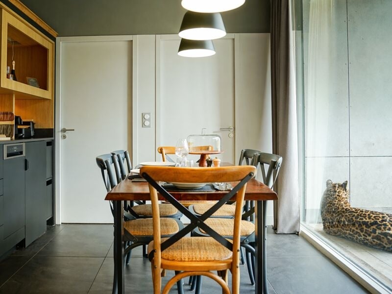 Salle à manger avec table en bois, chaises variées, grande baie vitrée et décoration intérieure moderne.