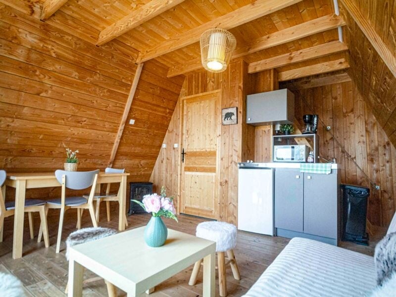 Coin repas et kitchenette en bois avec table, chaises, micro-ondes, cafetière et décoration simple.
