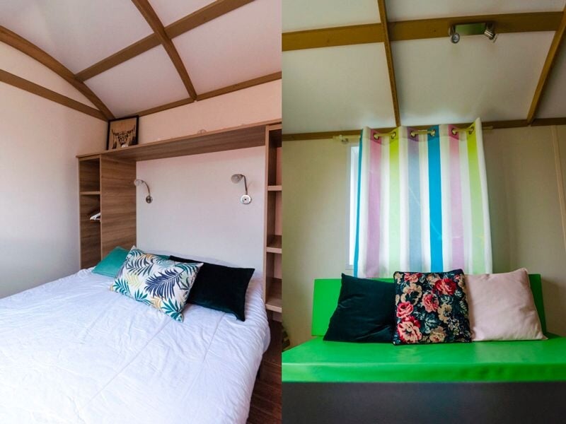 Chambre avec lit double, coussins décoratifs, étagères en bois et murs clairs sous un plafond voûté.