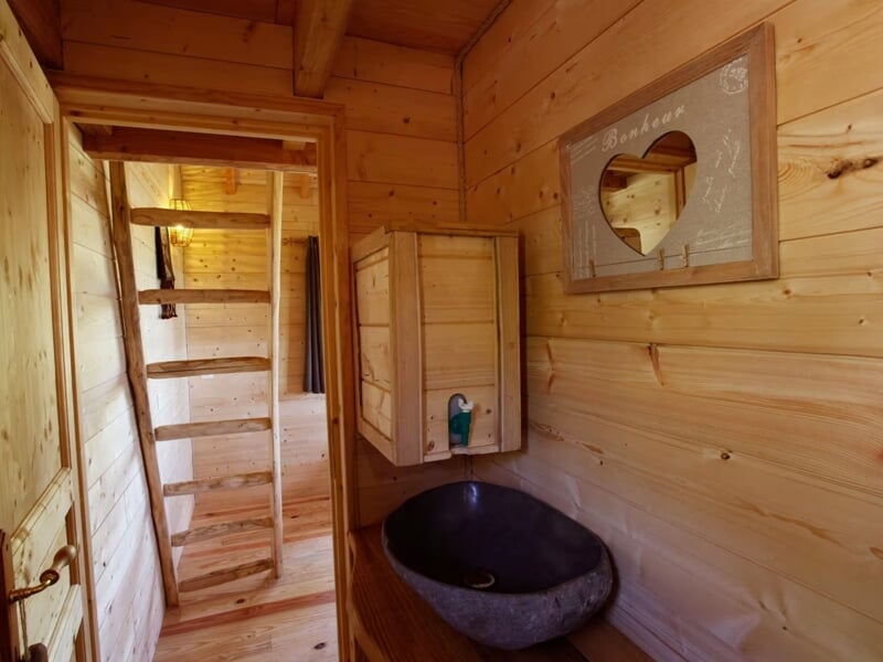 Coin lavabo en pierre avec miroir en bois et décoration murale dans une pièce en bois clair.