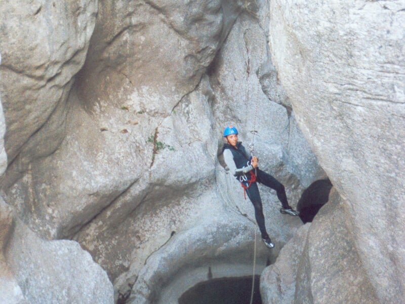 Personne escaladant une paroi rocheuse équipée pour la via ferrata avec un casque et un harnais