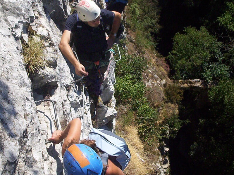 Personne en train de grimper sur une via ferrata avec un casque et un harnais de sécurité