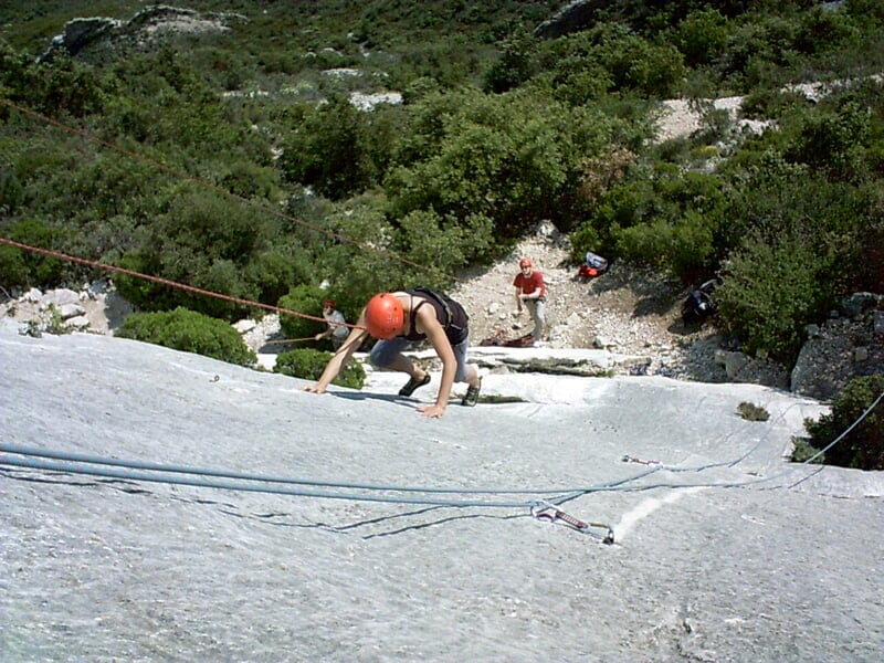 Escaladeur équipé pour la via ferrata progressant sur une paroi rocheuse avec un casque