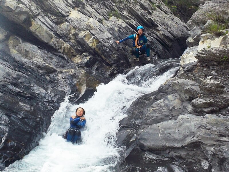 Groupe de personnes en canyoning progressant dans un canyon avec de l'eau et des rochers