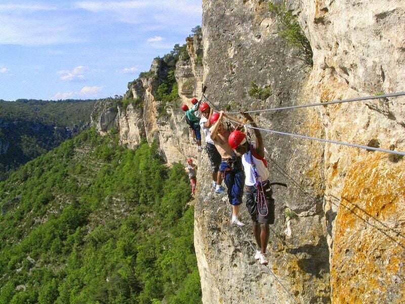 Escaladeur équipé pour la via ferrata progressant sur une paroi rocheuse avec un casque