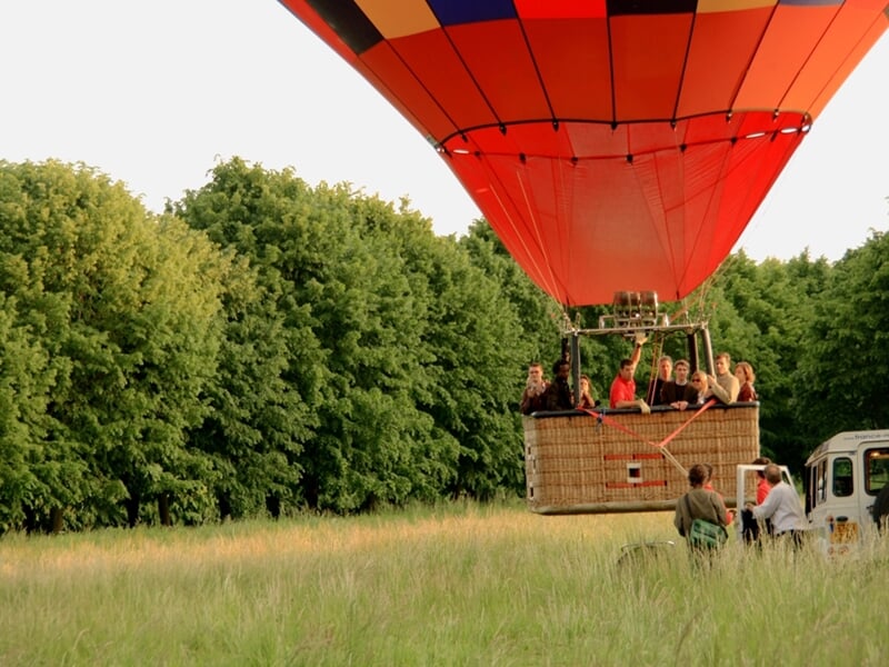Des touristes dans la nacelle d'une montgolfière dans une prairie avant le décollage