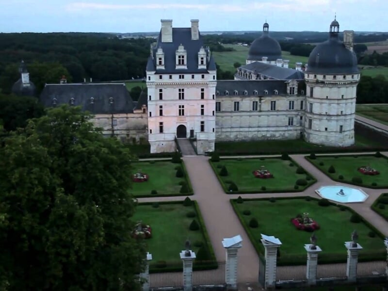 Montgolfière colorée survolant un paysage rural avec des champs et des collines vertes