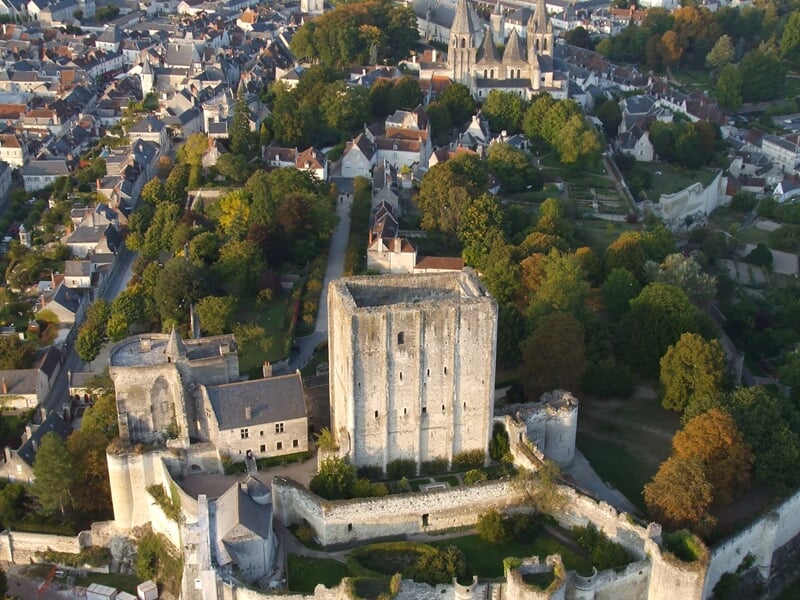 Montgolfière colorée survolant un village médiéval perché sur une colline au coucher du soleil