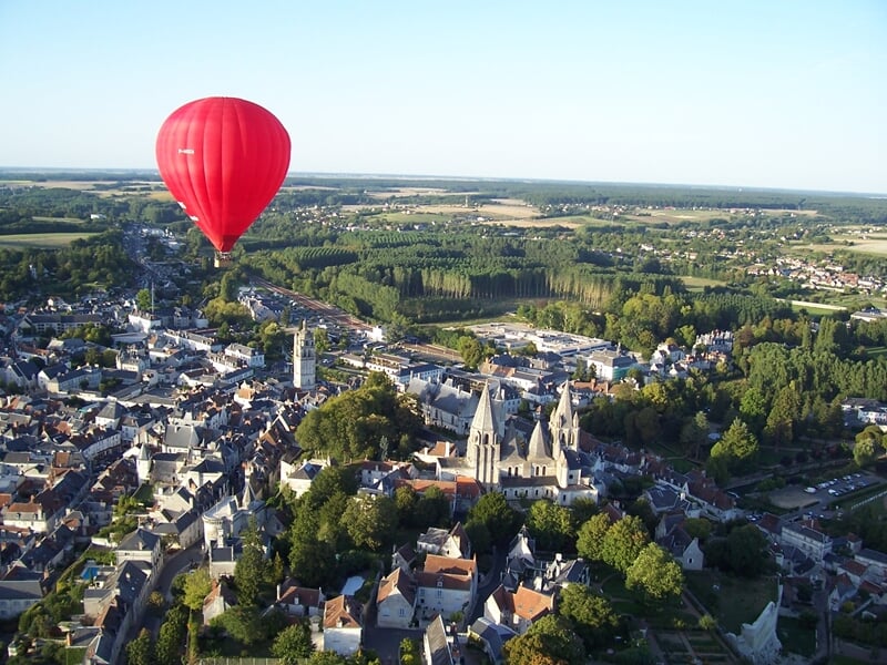 Montgolfière colorée survolant un village médiéval perché sur une colline au coucher du soleil