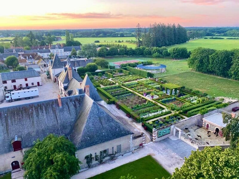 Montgolfière colorée survolant un château entouré de verdure et d'un lac