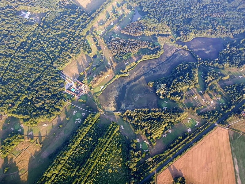 Montgolfière colorée survolant un château entouré de verdure et d'un lac