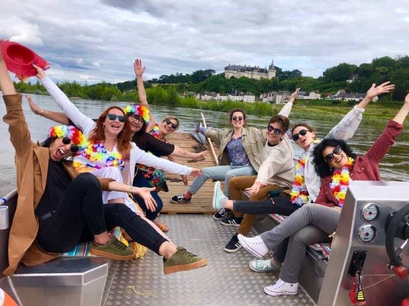 Groupe d'amis souriants lors d'une balade en bateau sur la Loire, près de Blois, décor naturel et château en arrière-plan.