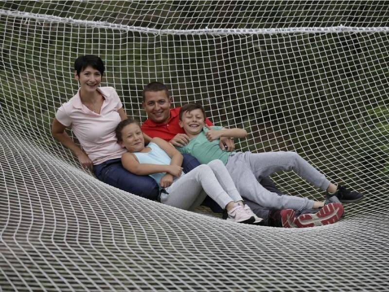 Famille de quatre personnes, allongées sur un grand filet suspendu, souriantes et détendues, près de Blois.