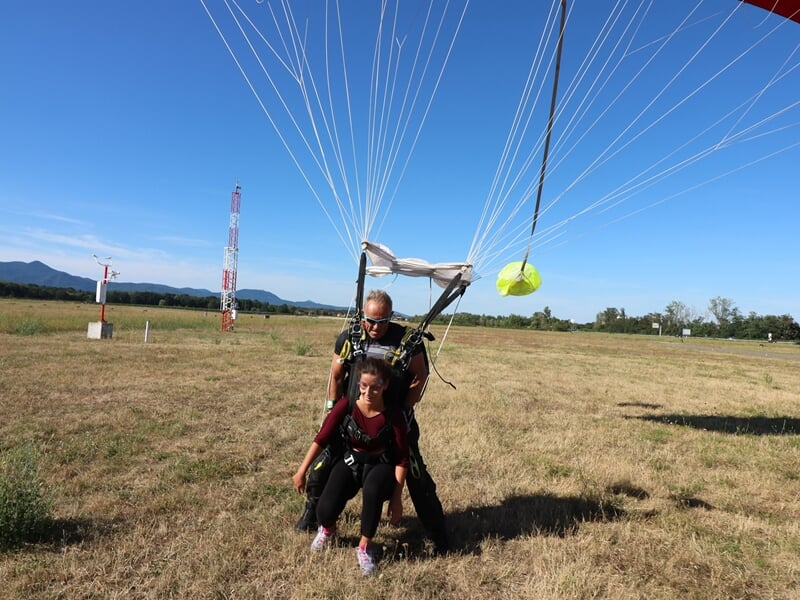 Parachutiste atterrissant en douceur sur un champ herbeux avec un instructeur en tandem.