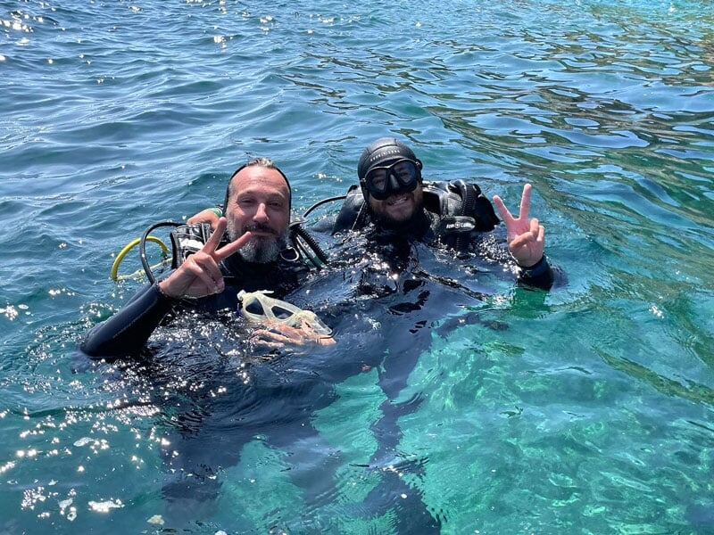 deux plongeurs sont dans l'eau avec des tenues de plongée