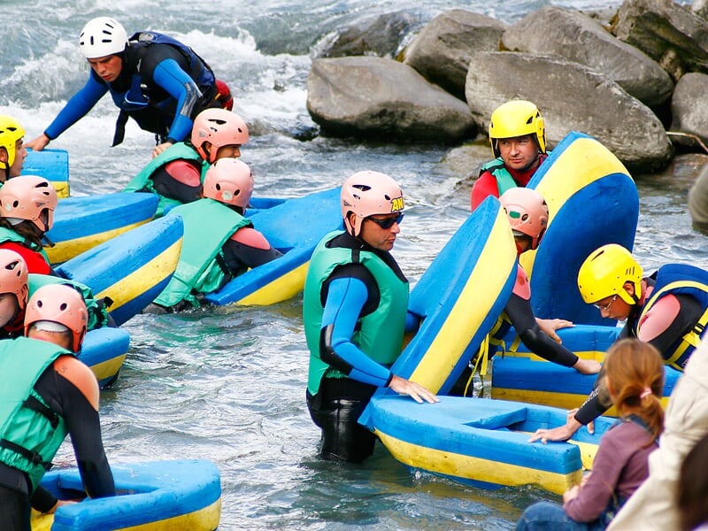 Groupe de personnes en combinaison et casque se préparent à l'hydrospeed au bord d'une rivière rocheuse.