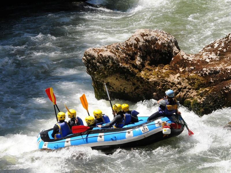 Deux hommes en kayak bleu pagaient dans une rivière agitée avec des éclaboussures d'eau.
