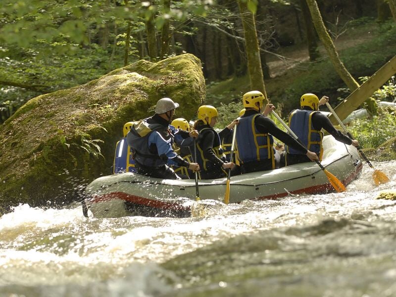 Un couple en kayak pagaient ensemble dans une rivière avec des rapides et eau vive.